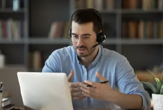 hombre joven con audífonos y micrófono frente a una pantalla explicando